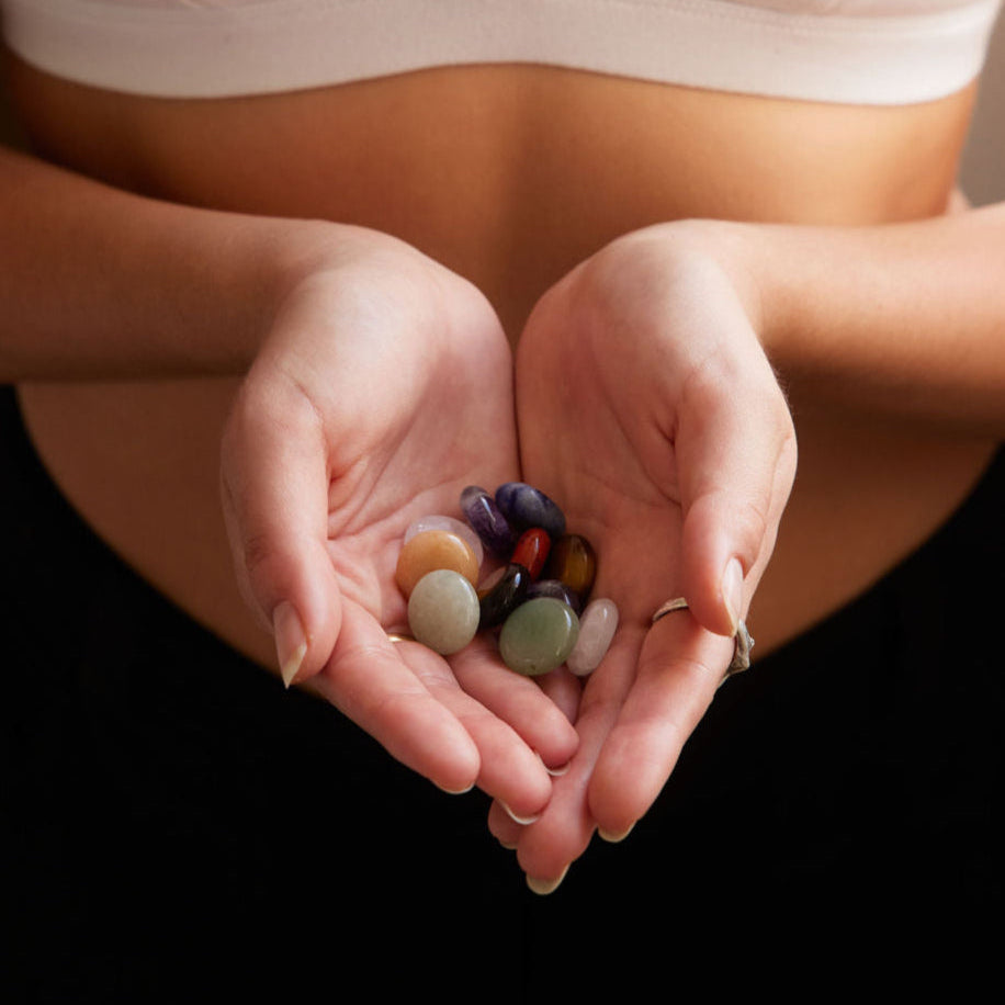 Person holding colourful pocket crystals  in their hands wearing a white Alma bralette.