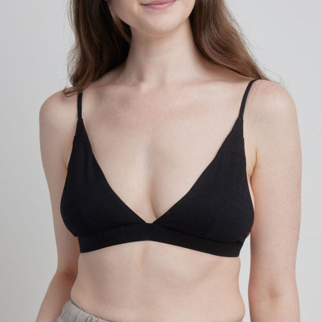 Woman wearing a black Alma bralette against a plain background