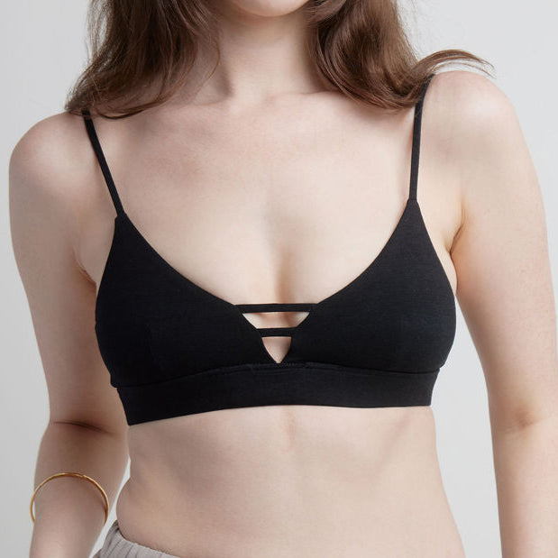 Woman wearing a black Alma bralette against a plain background.