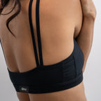 A woman wearing a black Alma bralette, stretching to the side.