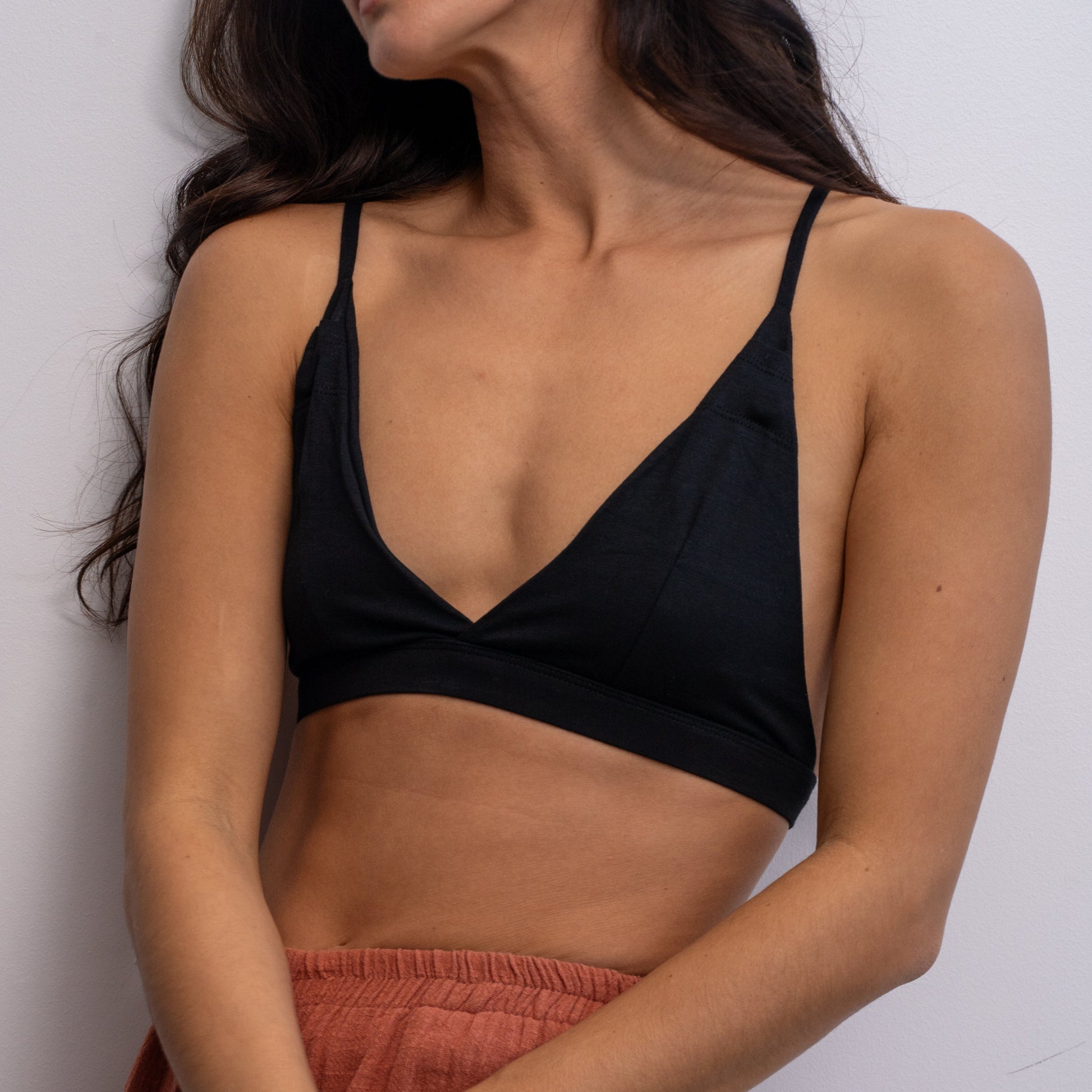 Woman wearing a black Alma bralette against a plain background.