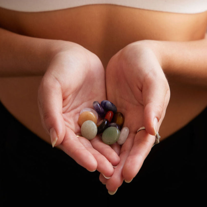 Hands cupped together holding multicoloured Alma pocket crystals.