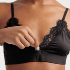 Woman wearing a sustainable bralette with pockets to hold crystals, worn for daily mindfulness, and slipping a crystal into a subtle front pocket of the bralette.