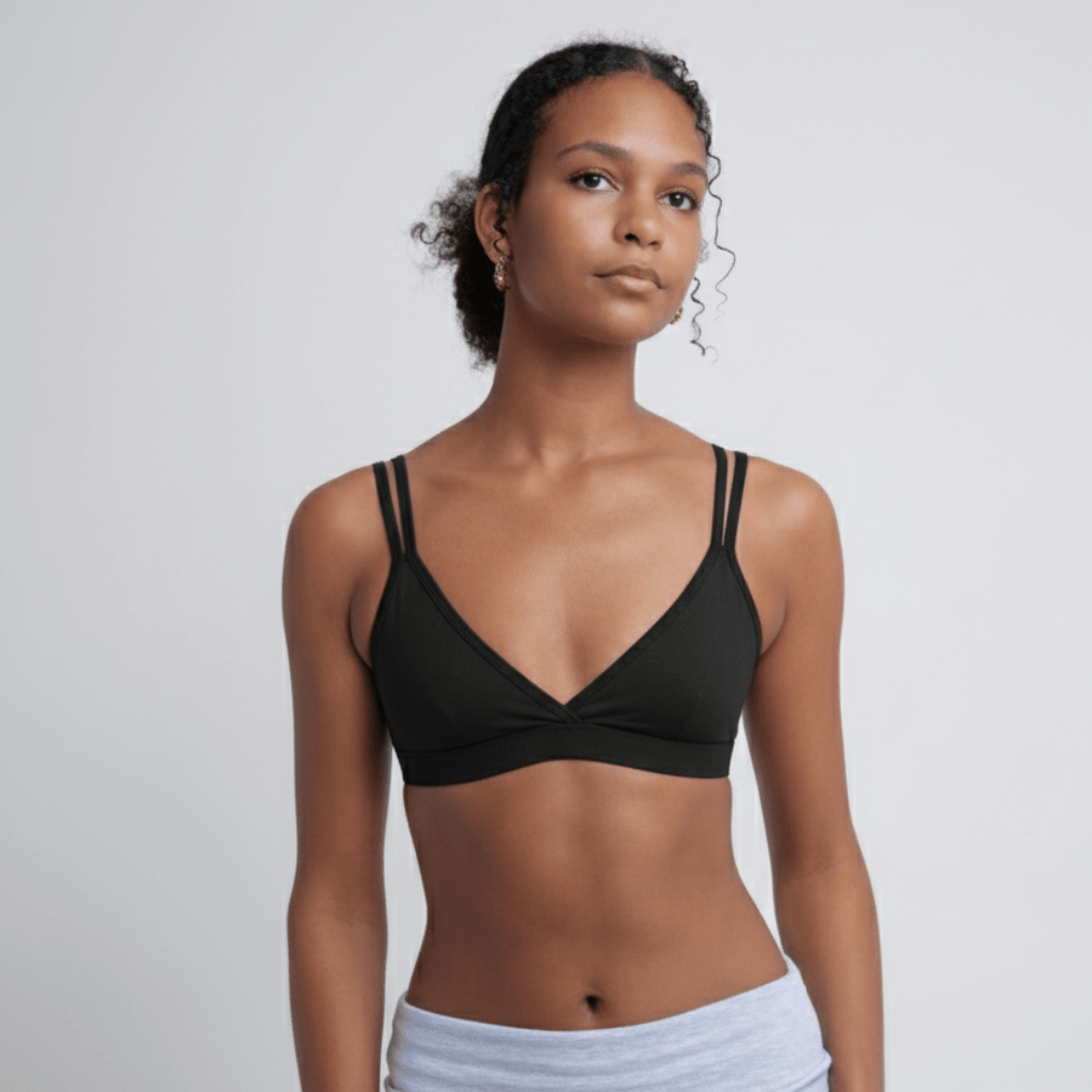 A front shot of a woman wearing a black Alma bralette and grey leggings.