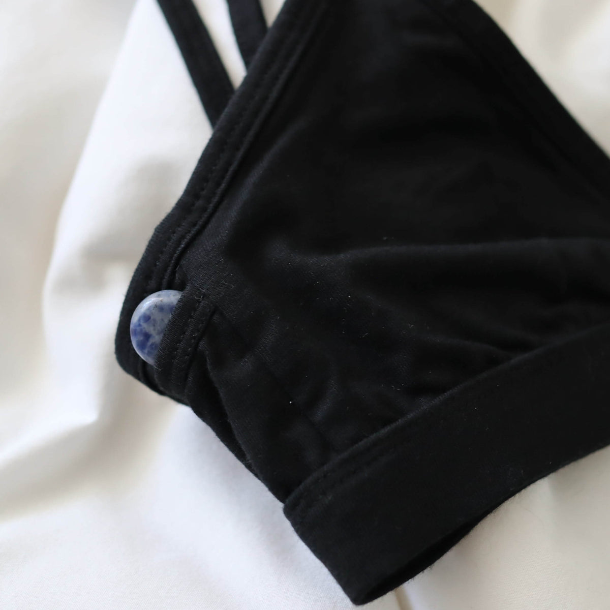 A focused shot of an Alma bralette with a Sodalite pocket crystal peeking out of a subtle side pocket of the bralette.