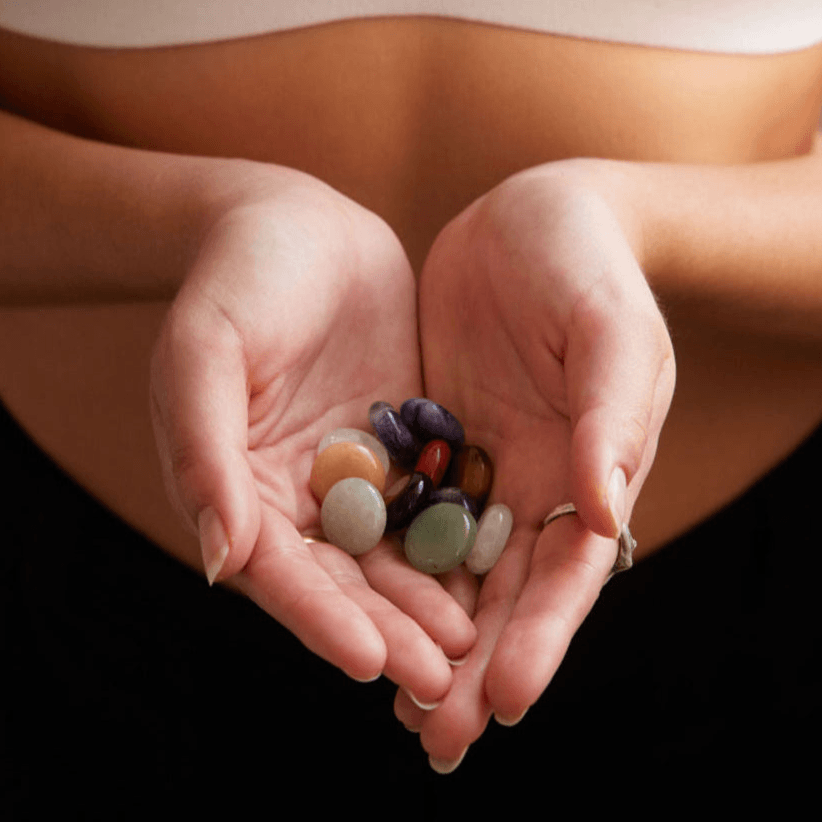 A woman's hands cupped together holding multicoloured Alma pocket crystals, used for mindfulness, calmness and clarity.